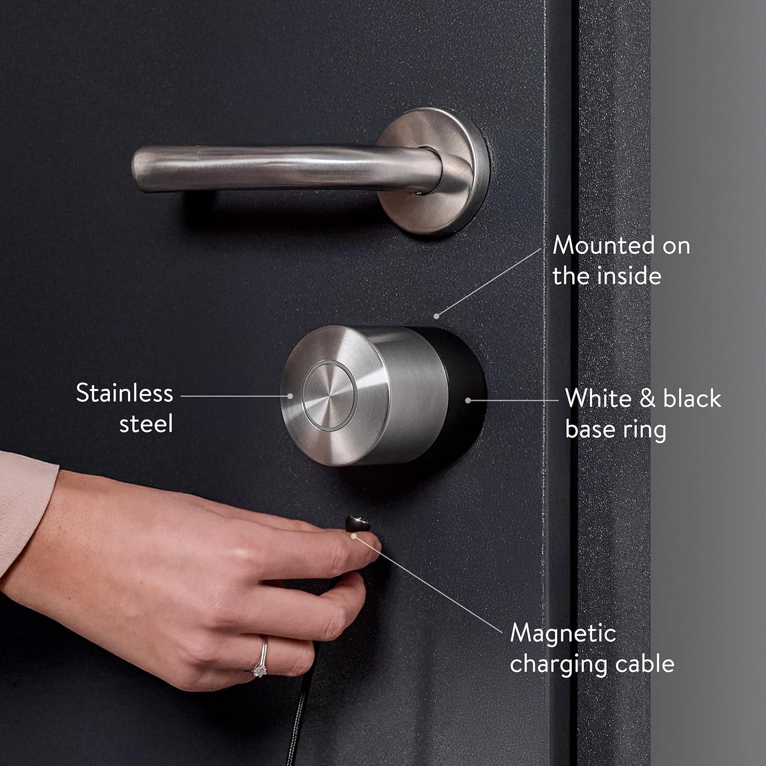 Nuki Smart Lock Pro mounted on the inside of a dark front door with the magnetic charging cable attached
