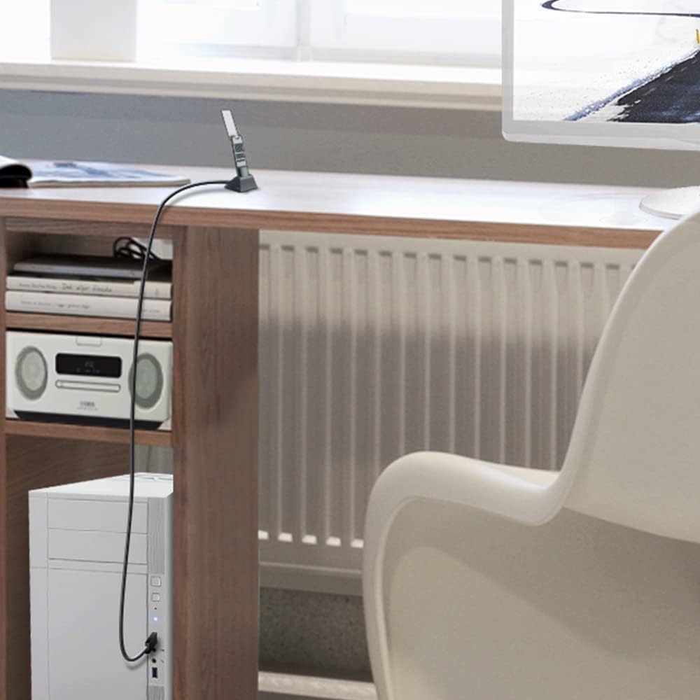 The TX20UH dongle standing upright in its cradle on a desk with the long USB cable running down to a tower PC on the floor